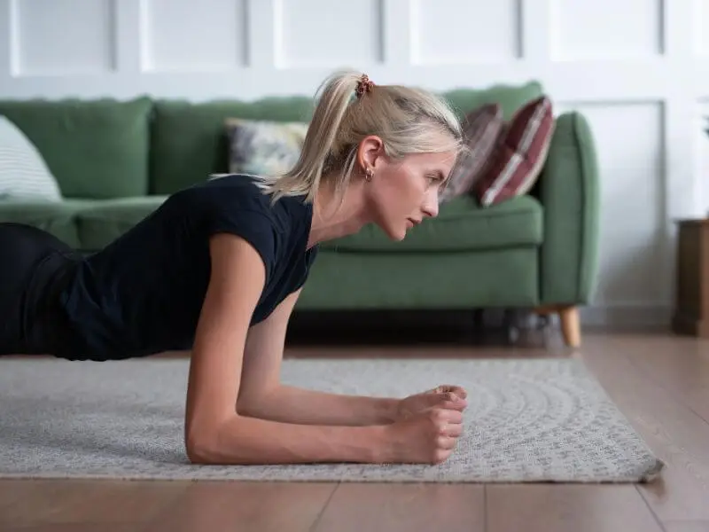 Mulher executando prancha abdominal, demonstrando fortalecimento de core e melhora da postura.